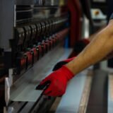 a man wearing red gloves is working on a machine