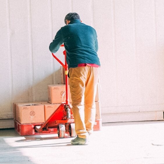 a man standing next to a red cart in a garage